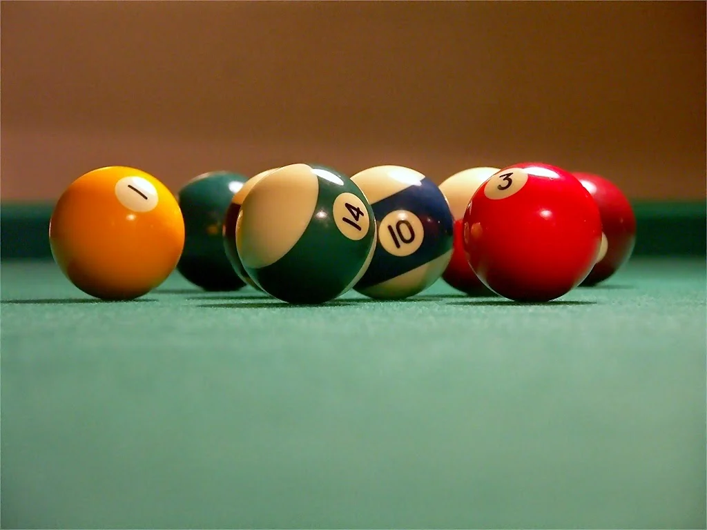 Billes numérotées alignées sur le tapis vert d’une table de billard.